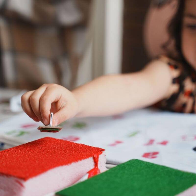 Mano de una niña untando un sello de tinta roja