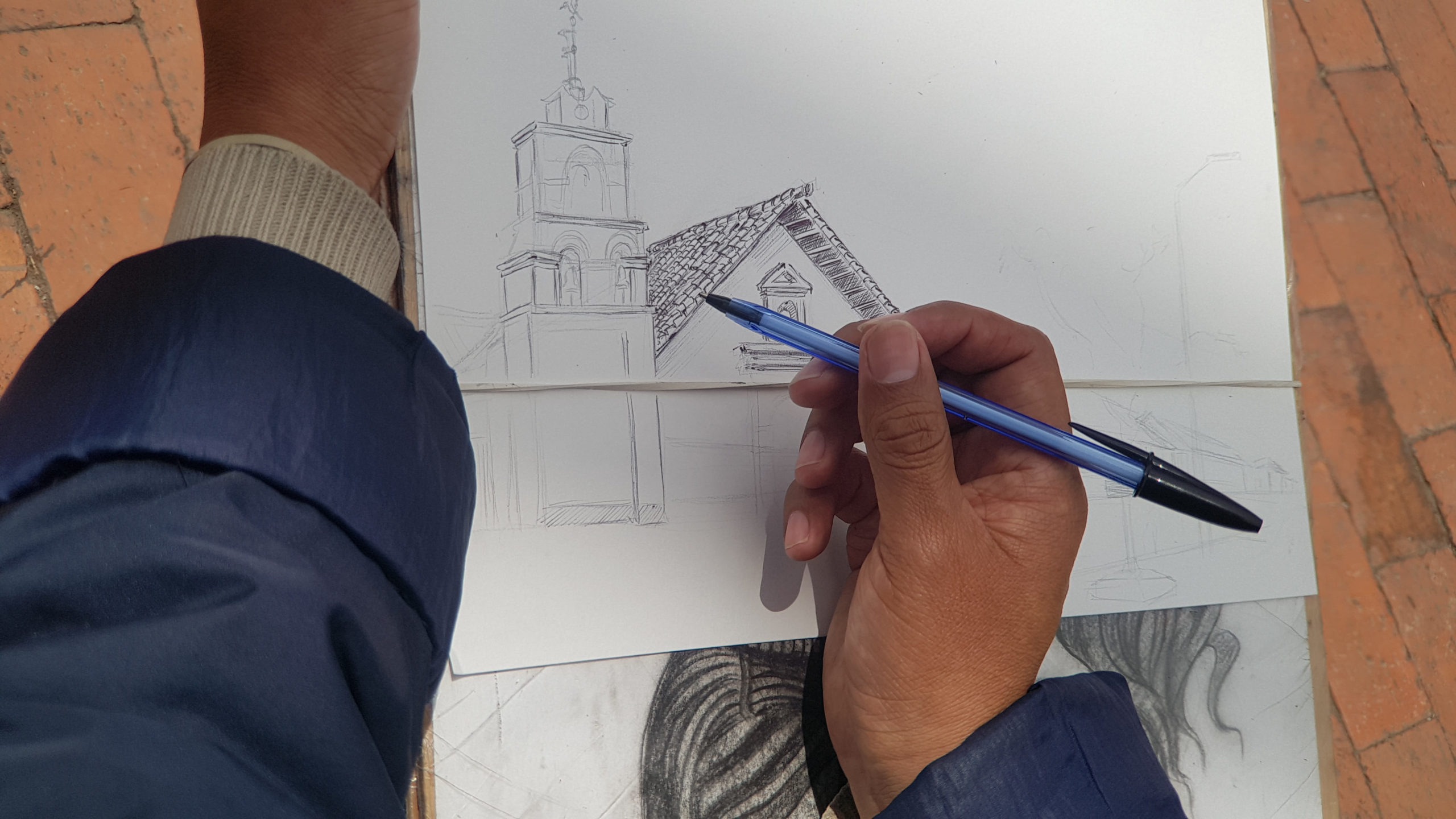 Persona realizando un dibujo a lápiz de una parroquia