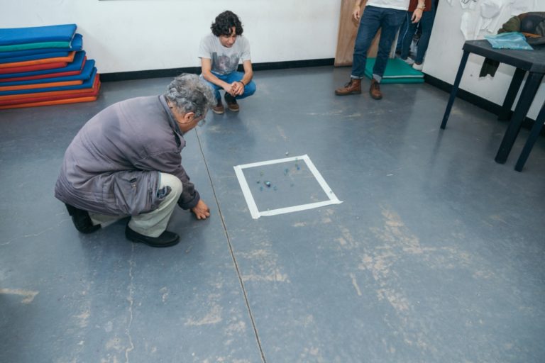 Persona adulta realizando una dinámica pintando un cuadro en el piso
