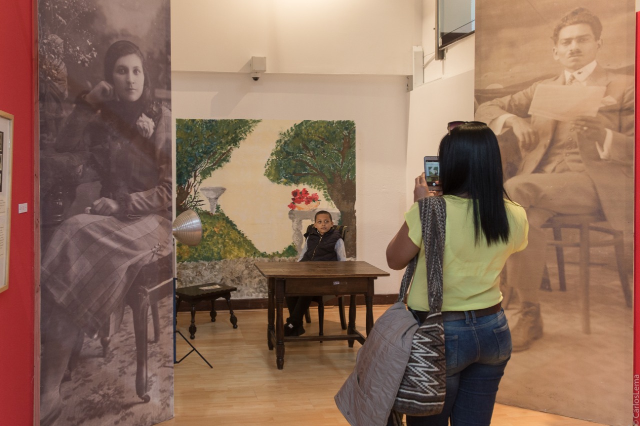 Mujer tomando fotografía de un niño en la exposición Temporal Álbum Familiar en la sede Casa Sámano del Museo de Bogotá