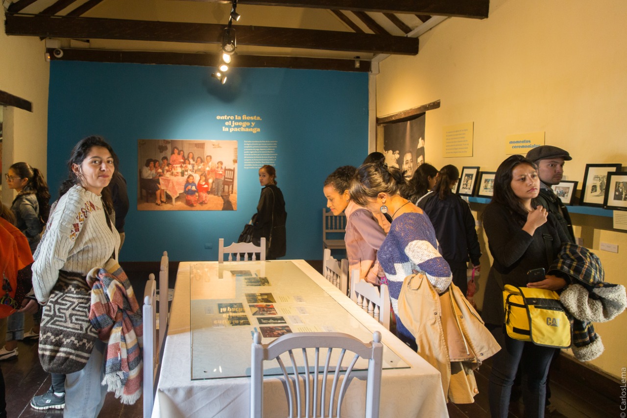 Grupo de mujeres y hombres observando cuadros fotográficos en la exposición Temporal Álbum Familiar en la sede Casa Sámano del Museo de Bogotá