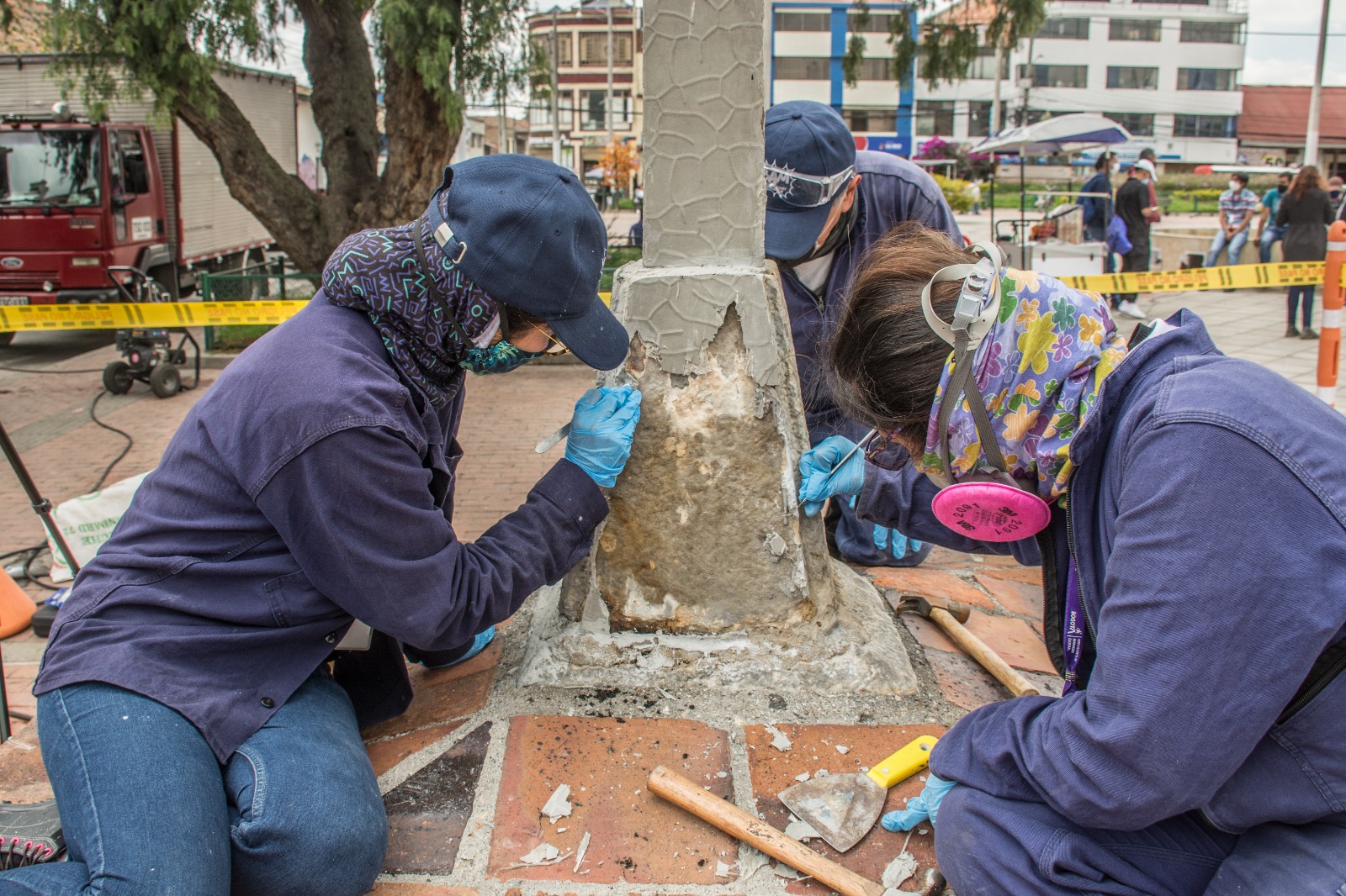 Tres personas trabajando en una columna de cemento.