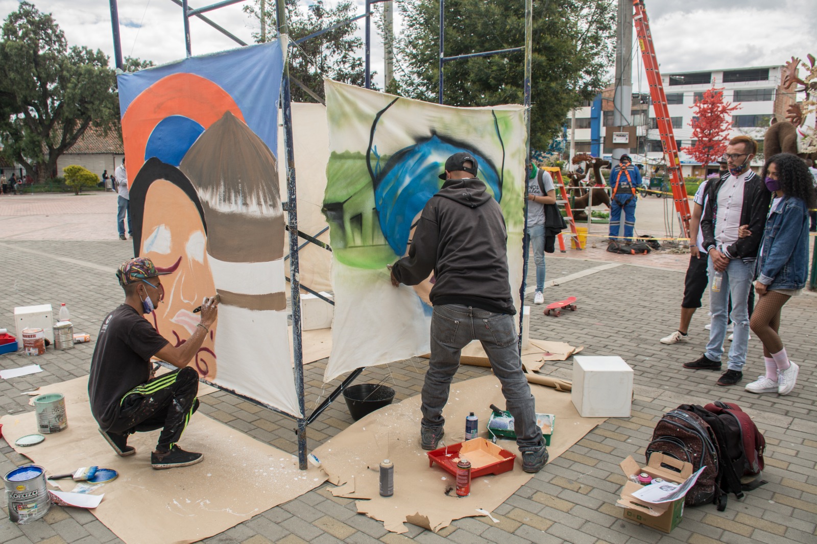 Hombres pintando en lienzos en la calle ante espectadores