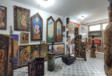 Espacio de galería artística con varios cuadros y esculturas exhibidas.