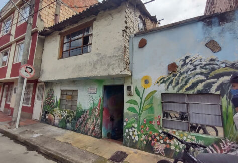 Entrada de una casa con un gran mural de un jardín de flores pintado en la pared de entrada.
