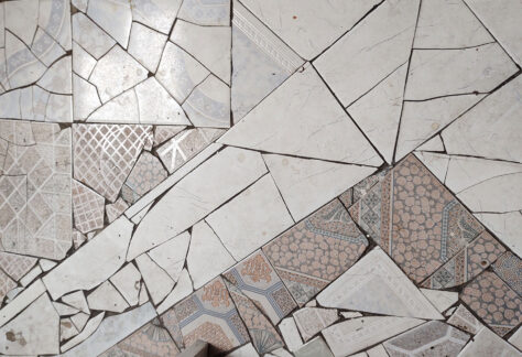 Piso de una casa con un mosaico elaborado con varias piezas de cerámica, principalmente blanca, sin la representación de una figura específica.