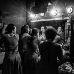 un grupo de actores de la obra teatral Salida al sol, camino a la paz, se prepara frente al espejo del camerino para la función.