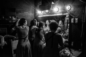 un grupo de actores de la obra teatral Salida al sol, camino a la paz, se prepara frente al espejo del camerino para la función.