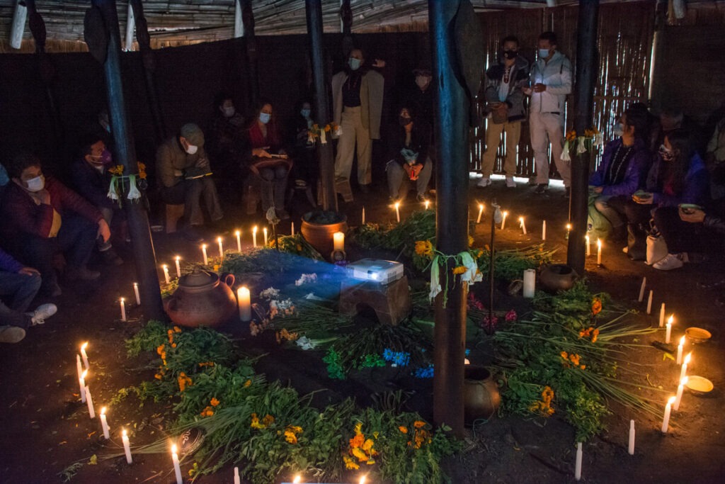 ritual Jizca Chia Zhue Hombres y mujeres alrededor de un mandala de yerbas dulces y velas en el cusmuy del Cabildo Índigena Muisca de Bosa