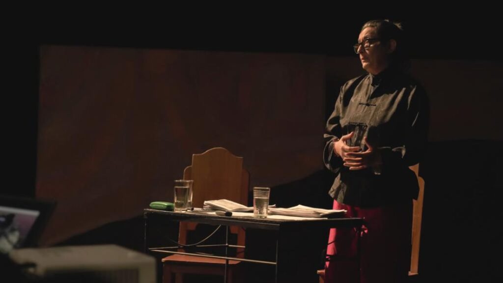 Persona frente a mesa con vasos y papeles durante la presentación de la Declaratoria de usos y la proyección artística y social del teatro de creación colectiva en Bogotá