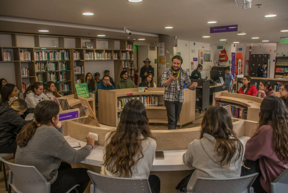 Hombre hablando a personas sentadas en la biblioteca del MCA