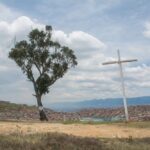El palo del ahorcado con la cruz al lado y ciudad bolivar al fondo
