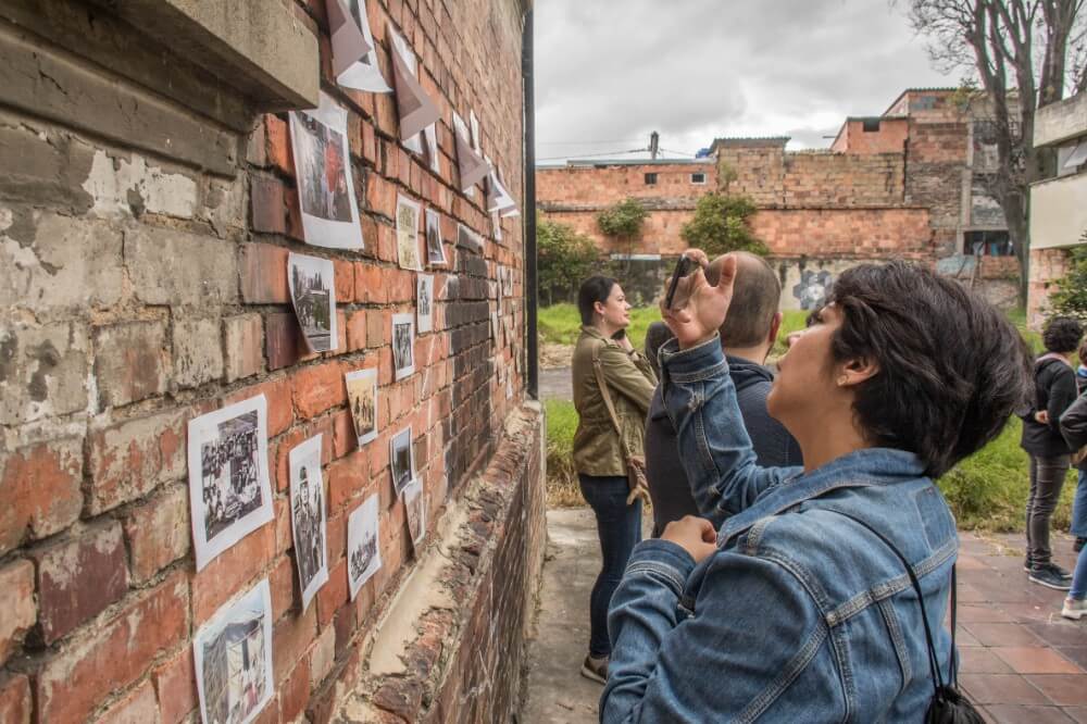 Personas viendo una pared con fotos antiguas durante un recorrido por el San Juan de Dios