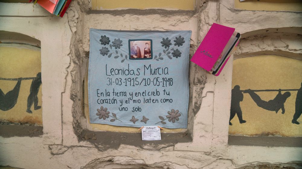 Tela azul con el nombre de Leonidas Murcia y uno de los diarios de la actividad presentado sobre una de las bóvedas de Columbarios.