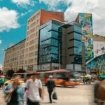 Una animada escena callejera en el Centro Histórico de Bogotá, con gente caminando en medio de una arquitectura histórica y la vida urbana.