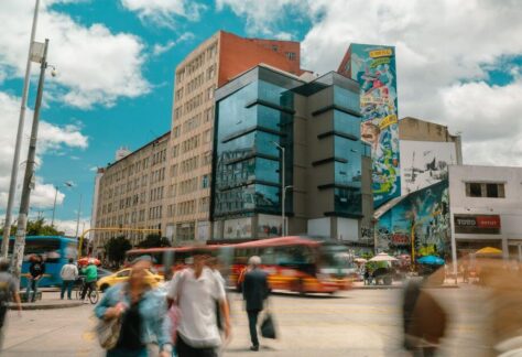 Una animada escena callejera en el Centro Histórico de Bogotá, con gente caminando en medio de una arquitectura histórica y la vida urbana.