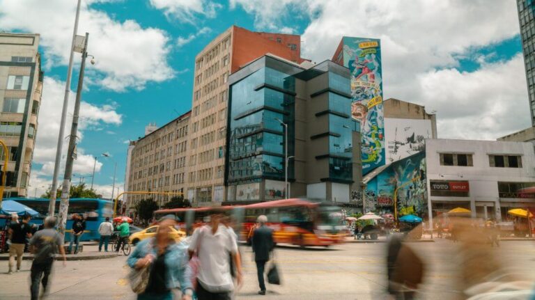 Una animada escena callejera en el Centro Histórico de Bogotá, con gente caminando en medio de una arquitectura histórica y la vida urbana.