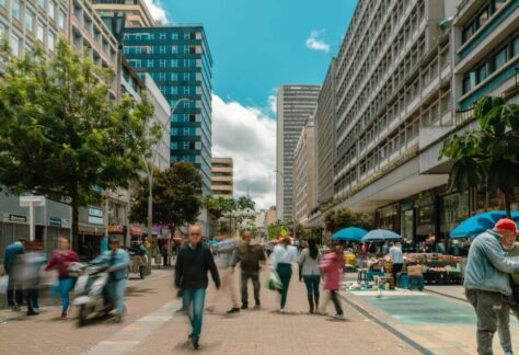 Gente paseando por una calle del Centro Histórico de Bogotá, con edificios históricos al fondo.