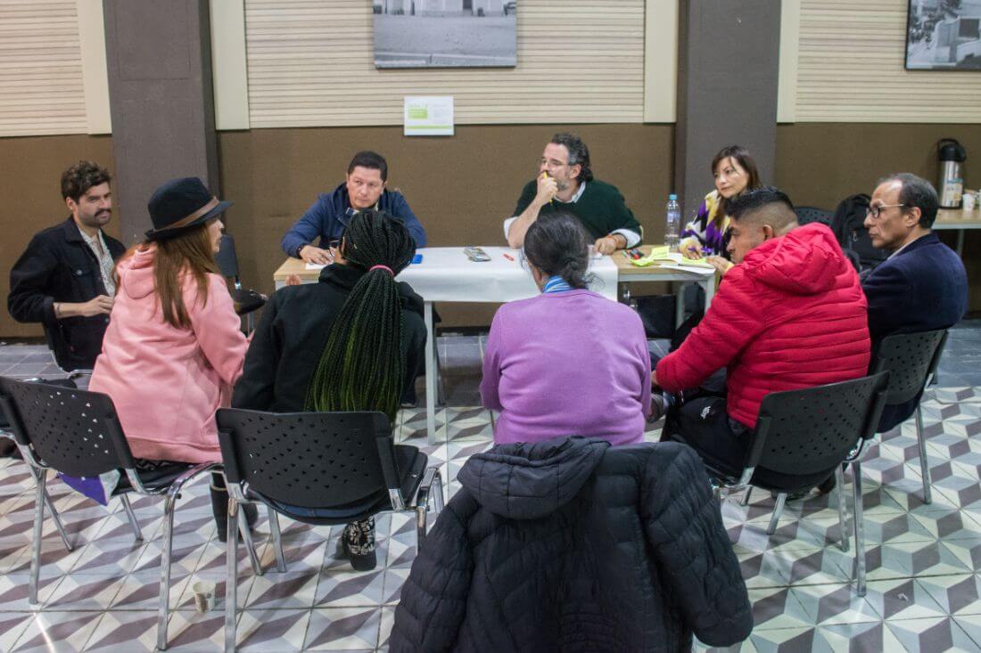 Grupo de personas sentadas alrededor de una mesa conversando del plan de desarrollo distrital