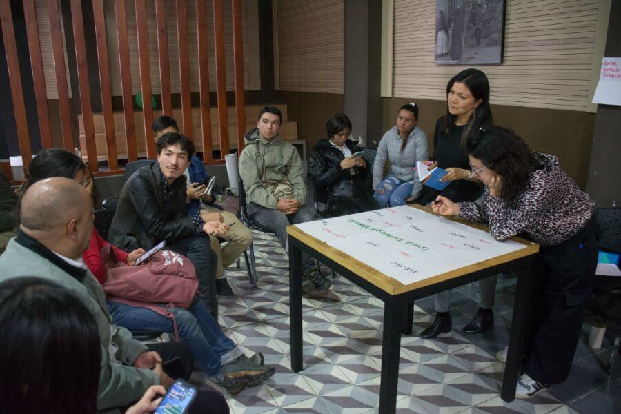 Grupo de personas sentadas alrededor de una mesa conversando del plan de desarrollo distrital