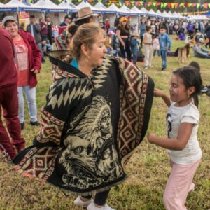 Mujer en ruana y niña bailan durante uno de los festivales de patrimonios en ruana