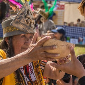 Mujer en vestimenta tradicional sostiene un tazón durante el festival Patrimonios en Ruana.