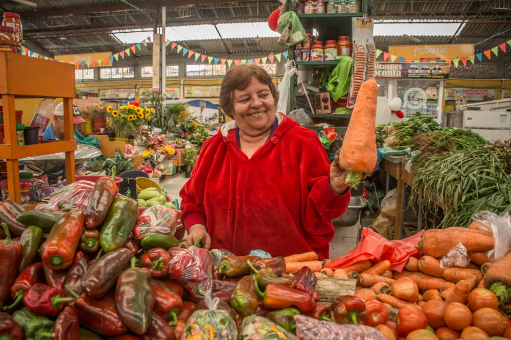 Mujer sonriendo muestra una zanahoria en la plaza galán