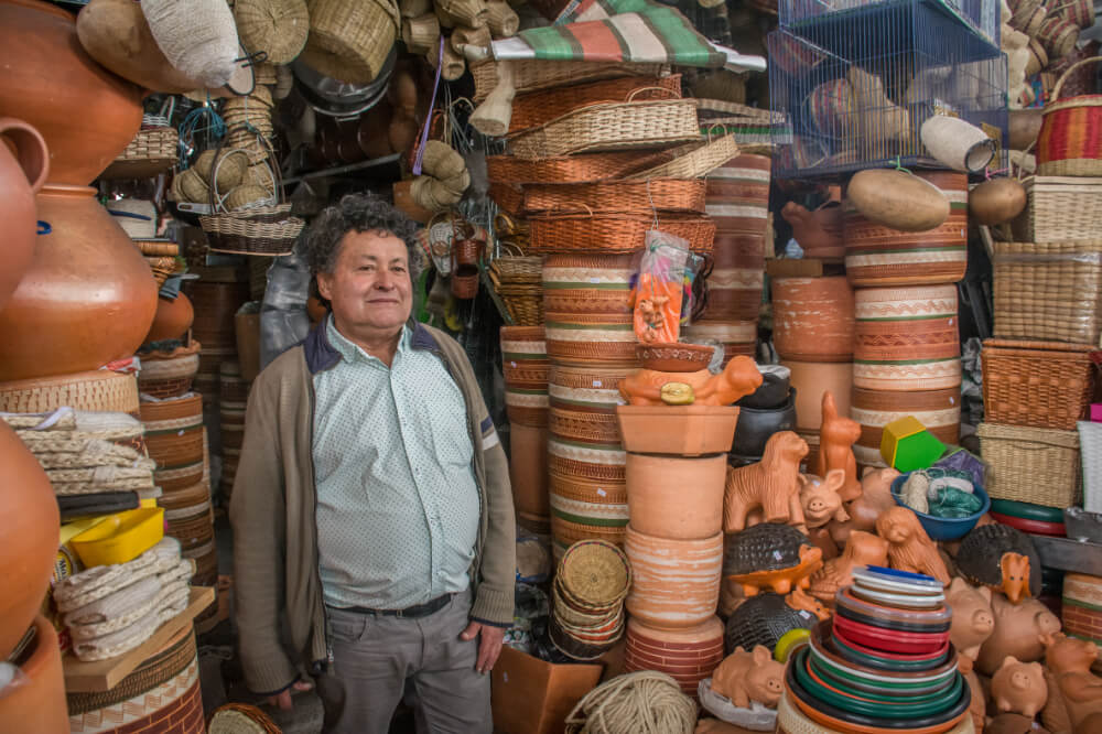 Hombre frente a artesanias de barro en la plaza qurigua