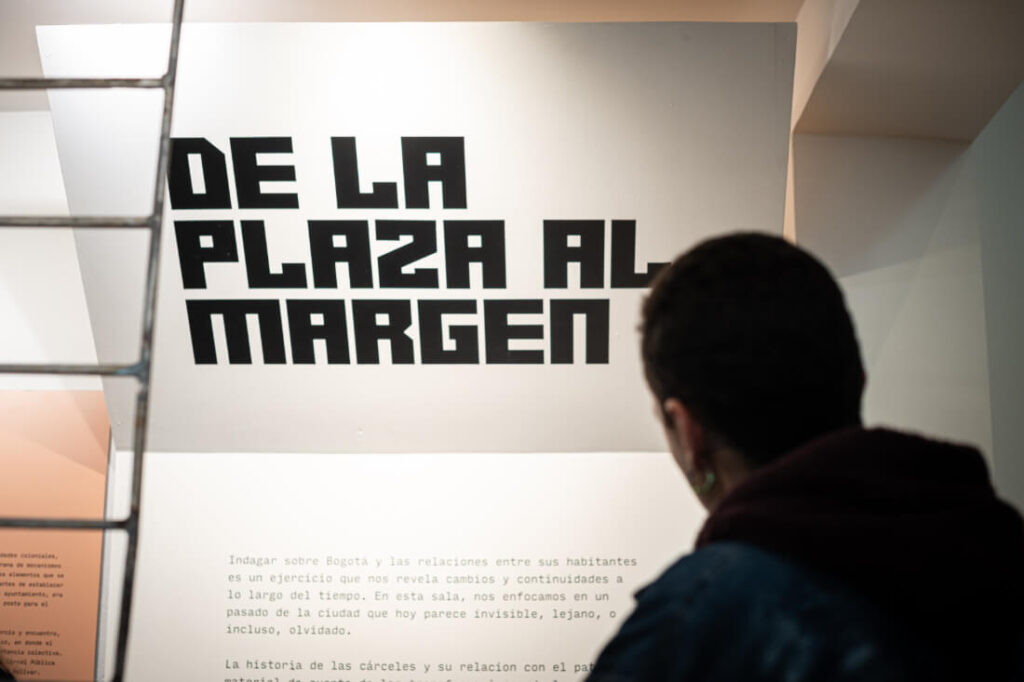 Persona frente a cartel De la plaza al margen