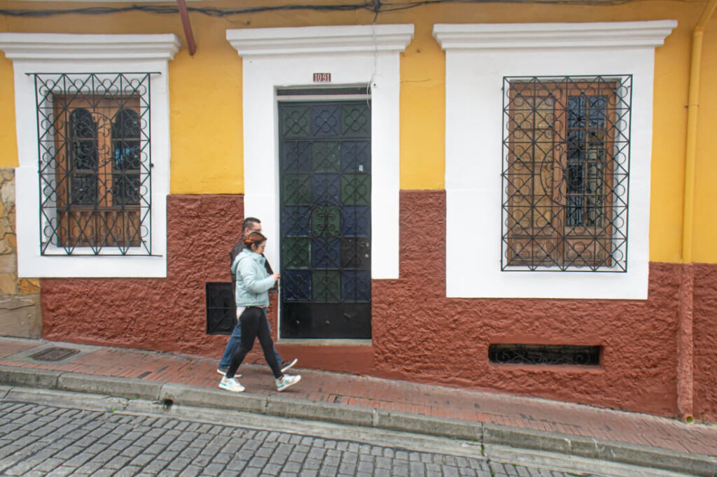 Dos personas caminan frente a fachada de la candelaria