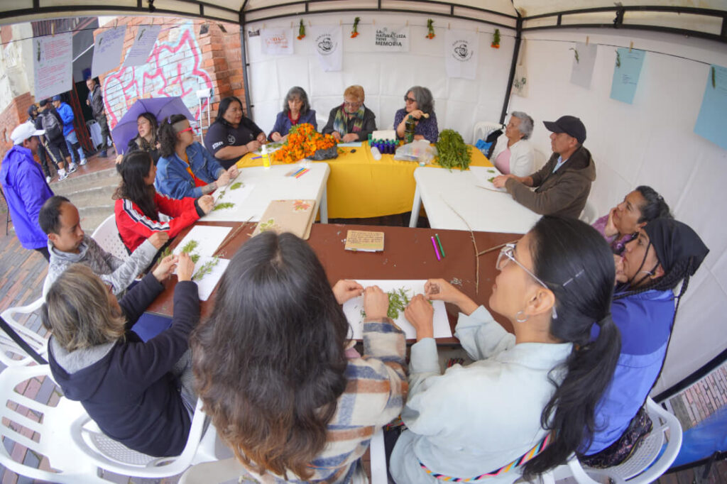 Personas reunidas al rededor de una mesa participan de actividad en el barrio las cruces
