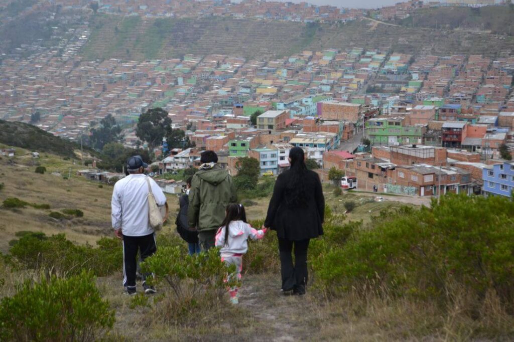 Personas caminan por la montaña con ciudad bolívar al fondo