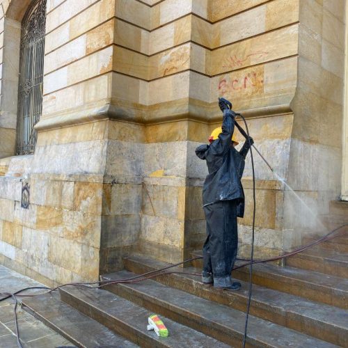 Integrante de la brigada de intervención al patrimonio lavando con agua a presion la fachada del palacio San Francisco