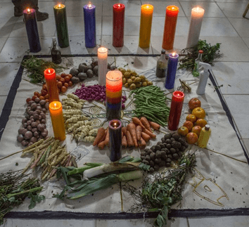 Un círculo de velas y verduras sobre el suelo, decorando el festival Jizca Chia Zhue.