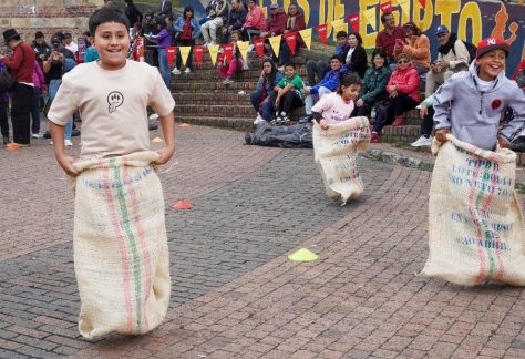 Grupo de niños participando en juegos tradicionales como carreras de sacos durante la Fiesta de Reyes Magos.