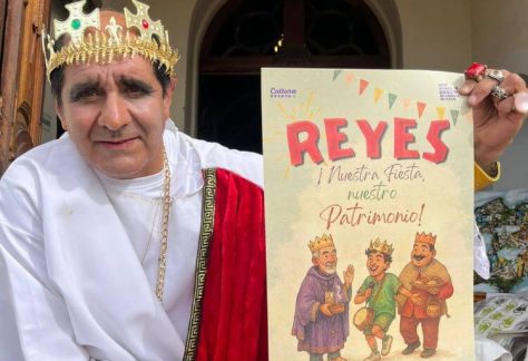 Hombre vestido como Rey Mago sostiene un cartel promocional del evento Reyes y Fiesta de la Epifanía