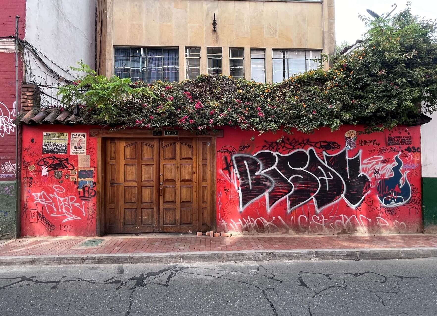 Fachada de color rojo en el centro histórico con graffitis antes de ser intervenida