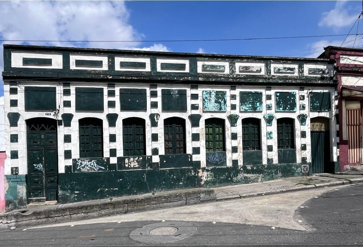 Fachada del centro historico de color verde y blanco con grafittis antes de ser intervenida