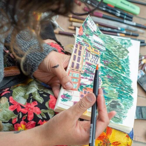 Detalle de manos ilustrando una escena de Bogotá en acuarela.