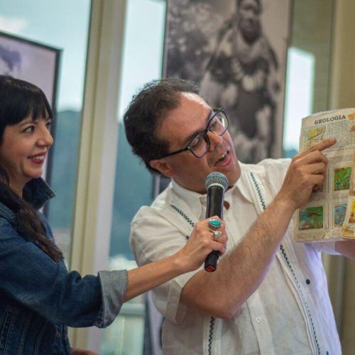 Presentadores mostrando páginas de un libro antiguo durante la conversación.