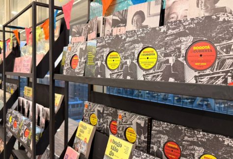 Estanterías del stand editorial con publicaciones del IDPC y personas observando los libros.
