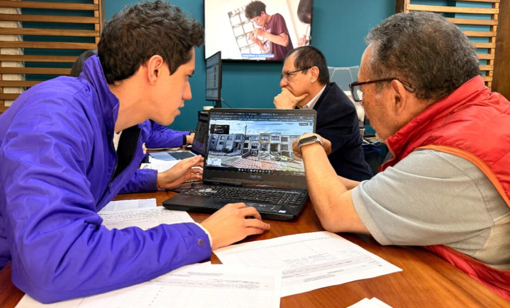 Equipo técnico del IDPC enseñando herramientas digitales y cartografía urbana a un ciudadano durante la jornada de atención.
