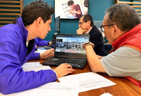 Equipo técnico del IDPC enseñando herramientas digitales y cartografía urbana a un ciudadano durante la jornada de atención.
