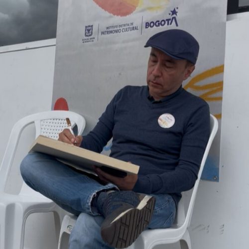 Dibujante sentado en una silla realiza una ilustración en vivo durante el Premio Dibujatón 2025.