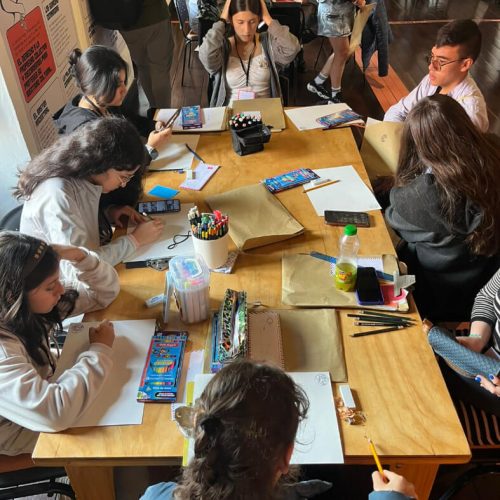 Vista general de una mesa larga donde adolescentes participan en el Premio Dibujatón.