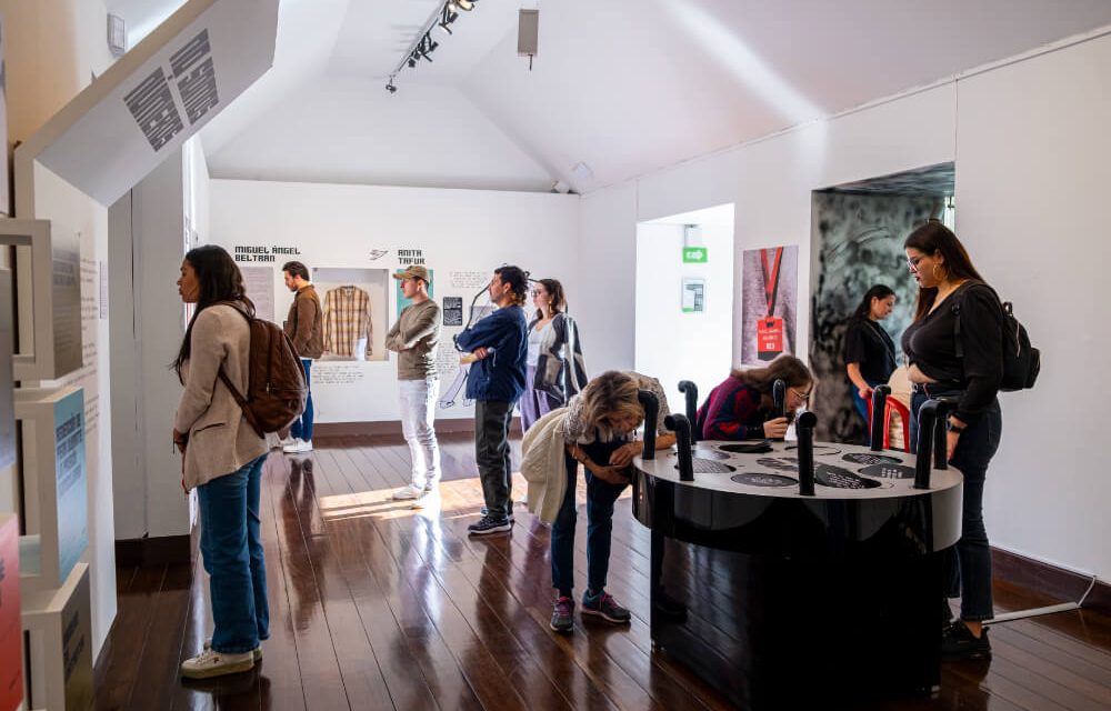 Público participa en una actividad interactiva en sala, observando y manipulando dispositivos de la exposición Pabellón Libertad.