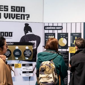 Personas leen gráficos y datos sobre población privada de la libertad en un módulo informativo de la exposición.