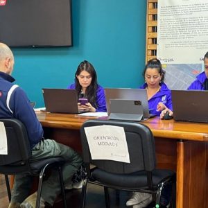 Funcionarios trabajando en computadores durante una jornada de atención a usuarios en una sala de servicio.