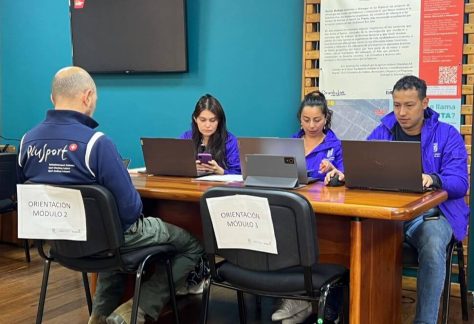 Funcionarios trabajando en computadores durante una jornada de atención a usuarios en una sala de servicio.