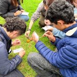 Un grupo de jóvenes trabajando en el suelo sobre sus dibujo